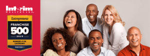 A group of recently laid off executives standing together, smiling and looking at the camera, with a professional setting in the background. They appear to be discussing a business opportunity, and their body language suggests collaboration and teamwork.